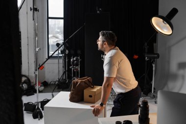 A professional man reviews his setup as he gets ready for an intense photo shoot session. clipart