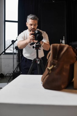 Odaklanmış biri fotoğraf makinesini bir sanat projesi için parlak bir stüdyoya yerleştirir..