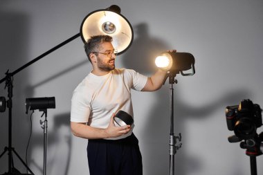 Man sets up lighting equipment in a well equipped studio, preparing for a photography session. clipart