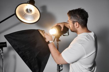 An expert in photography sets up a light source to enhance the visual impact of his work. clipart