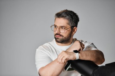 Gündelik giyinmiş bir adam modern, minimalist bir stüdyo içinde düşünceli bir şekilde çalışmalarını sürdürür..