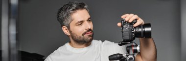 Odaklanmış adam çekim için kamera ekipmanlarını şık bir stüdyoda inceler..