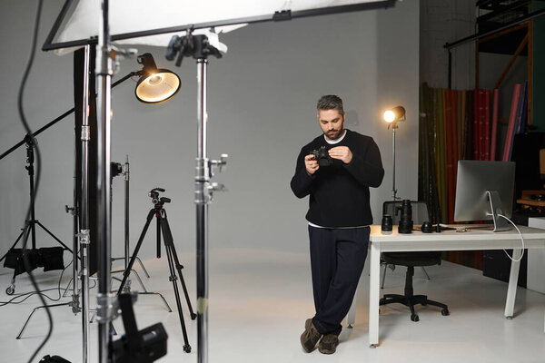 A dedicated man fine tunes his camera settings in a well equipped photography studio.