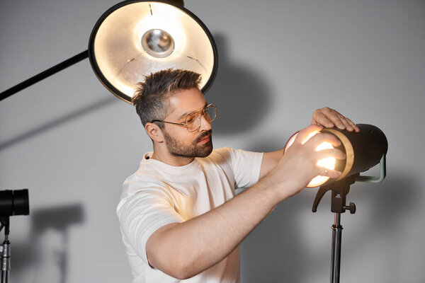 A man skillfully adjusts studio lighting equipment while preparing for a creative shoot.