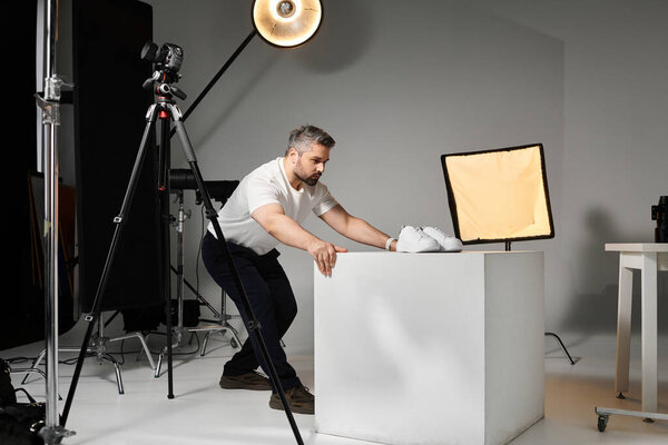 A skilled man focuses on arranging a product on a display in a contemporary studio environment.