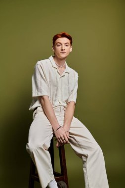 Yakışıklı bir genç adam düşünceli bir şekilde bir taburede oturur, sakin bir ortamda derin duygular ifade eder..