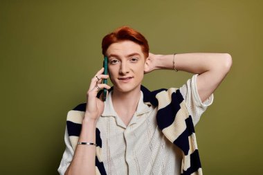 Genç ve yakışıklı bir adam telefonunda duygusal bir konuşma yaparken sıcak bir şekilde gülümser..