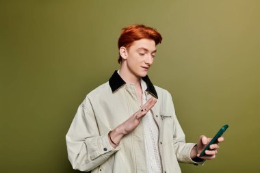 Duygusal genç adam akıllı telefonuyla iletişim kuruyor, modern uzayda sıcak bir gülümseme sergiliyor..