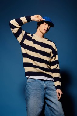 Genç bir adam şık bir poz verirken duygularını ifade eder, şapkasıyla oyuncu bir dokunuş yapar..