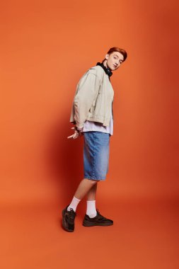 Yakışıklı bir adam parlak turuncu bir arka plana karşı güvenle durarak duygularını ifade eder..