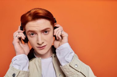 Kızıl saçlı, genç, yakışıklı bir adam kulaklıklarını ayarlarken müziğe dalmış..