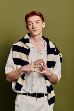 Kızıl saçlı genç bir adam derin duygular ifade eder. Katı bir arkaplanda zarifçe poz verir..
