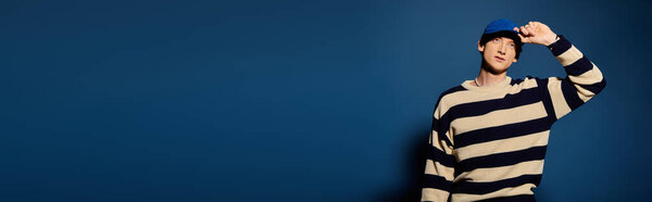 A young man in a striped sweater and cap shows deep emotion while posing gracefully.