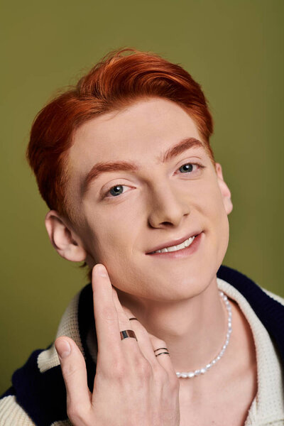 A young man with red hair shares his joy with a warm smile and playful spirit.