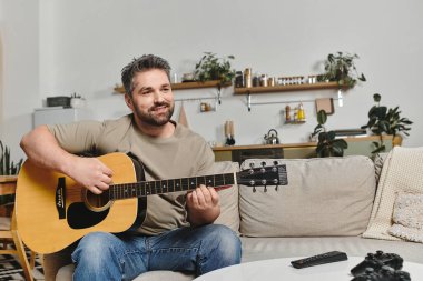 Bir adam rahat bir kanepede gitar çalar, müziğe dalmış ve yakınlarda sevdikleriyle sıcak bir evde..