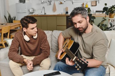 Genç bir adamın evdeki yakın bir arkadaşından gitar çalmayı öğrenmesi iç açıcı bir an..