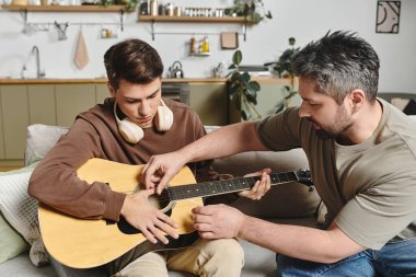 Rahat bir evde gitar çalmayı öğretirken iki kardeş sıcak bir anı paylaşıyor..