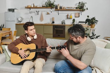 Genç bir adam evdeki ilgili bir yetişkinden gitar çalmayı öğreniyor..