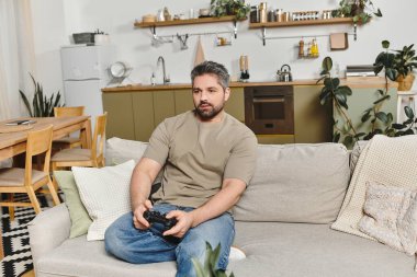 A man relaxes on a soft couch while gaming, surrounded by a stylish and cozy home interior. clipart