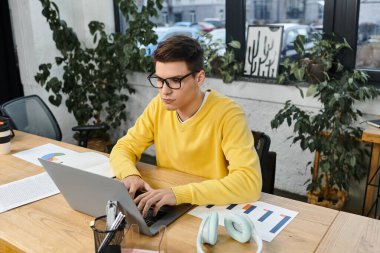 Sarı kazaklı odaklanmış bir birey şık bir ofis masasında görevlerini tamamlar..