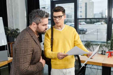 Yeni bir çalışan, parlak bir ofiste deneyimli bir meslektaşıyla iş sorumluluklarını tartışıyor..