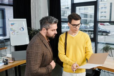 Two professionals collaborate during onboarding in a contemporary office space filled with light. clipart