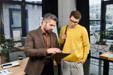 Two professionals in a contemporary office discussing onboarding details with enthusiasm. clipart