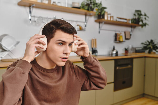 Молодой человек расслабляется в теплой домашней обстановке, сосредоточен на наушниках и теряется в звуке.