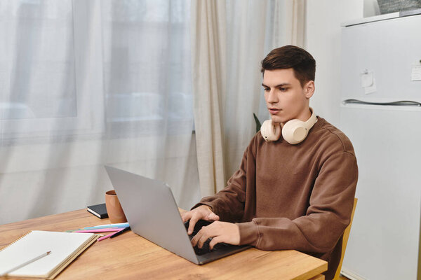 Молодой человек усердно работает над своим ноутбуком за деревянным столом в уютном, уютном доме.