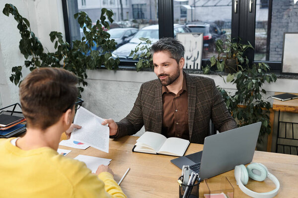 Two professionals interact at a desk in a stylish office space during an onboarding session.