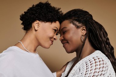 Two stylish women share a loving gaze, radiating joy and connection. clipart