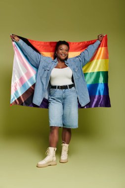 Bir kadın sevinçle bir LGBT bayrağı sergiliyor, stil ve güven yayıyor.