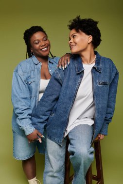 Stylish lesbian couple enjoys a warm and loving moment while dressed in trendy denim attire. clipart