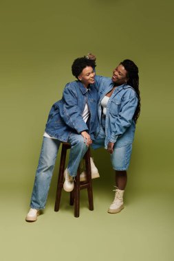 İki şık kadın, şık kotlar giyerken aynı kahkahayı ve sevgiyi paylaşıyor..