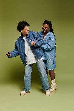 Tarz sahibi bir çift, canlı yeşil bir arkaplan önünde neşeyle etkileşime geçer, sevgi saçar..