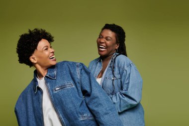 İki modaya uygun kadın neşeli bir anın tadını çıkarıyorlar, modaya uygun kot ceketler giyerken aşk yayıyorlar..