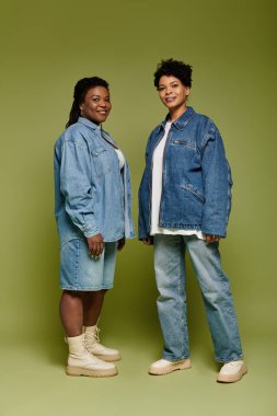 Modaya uygun giyinmiş iki kadın aynı anda giyiniyor, kendine güven ve tarz saçıyor..