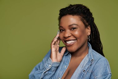 Yeşil zeytin arkaplanda poz veren hayat dolu elbiseli mutlu bir kadın..