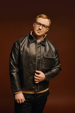 İyi görünümlü bir adam, stüdyo içinde kendine güvenen bir şekilde poz verir, modern moda sergiler..