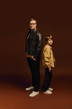 Baba ve oğul gururla poz veriyor, şık, sıradan kıyafetleriyle, neşeli bir bağın altını çizerek..