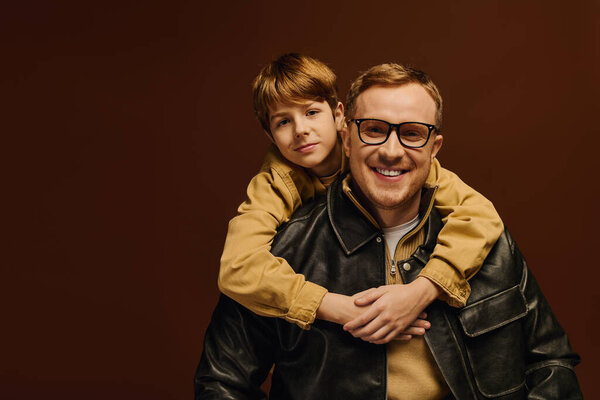Отец и сын разделяют радостный смех, одетые в повседневные наряды вместе.