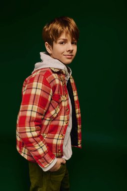 A preteen boy confidently poses in a checkered casual outfit inside a vibrant studio space. clipart