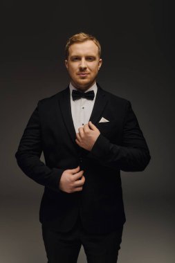 Şık bir adam şık bir smokinin içinde duruyor papyonlu, etkileyici bir cazibesi var.