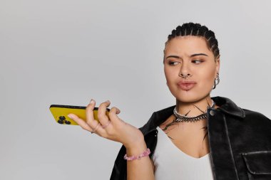 Moda bir kapalı mekanda, şık örgülü genç bir kadın rastgele telefonuyla meşgul oluyor..