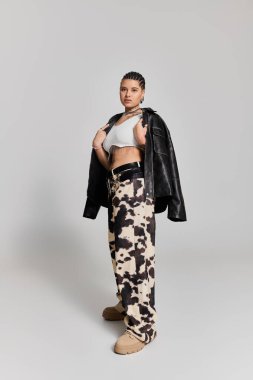 Genç bir kadın şık kıyafetini, modaya uygun bir duruşta, tarz ve tavırla sergiliyor..