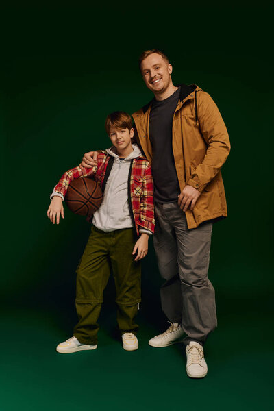 Веселый отец и сын счастливо позируют в согласованной повседневной одежде, демонстрируя семейную моду..