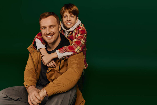 Отец и сын разделяют теплые объятия, счастливо позируя в повседневных нарядах..