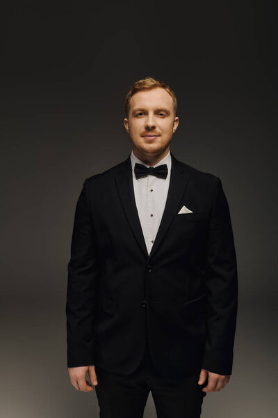 Красивый мужчина в смокинге излучает уверенность и очарование в студии..