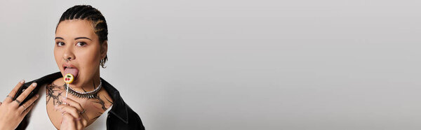 A trendy young woman indulges in a vibrant lollipop, expressing her unique style with confidence.