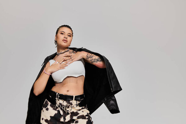 Молодая женщина демонстрирует свой модный наряд, принимая смелую позу, излучая уверенность и стиль.